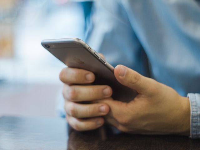 Händer håller i en mobiltelefon